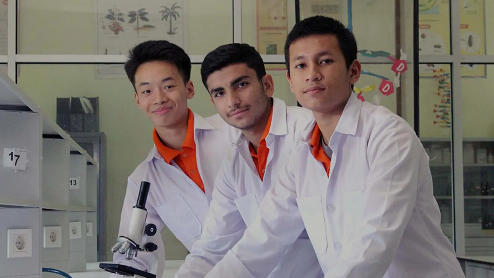 Tiga siswa berjas laboratorium di ruang praktikum Semesta